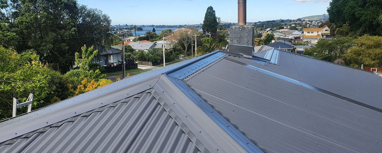 New corrugated roof with ridge capping and flashings installed by Mount Roof Services, looking out over Tauranga